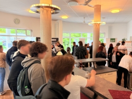 Junge Menschen stehen an einer Kaffeetheke in einem offenen Foyer