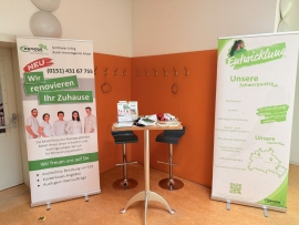 Zwei Roll-ups und ein Stehtisch mit zwei St&uuml;hlen stehen in einer Garderobenecke